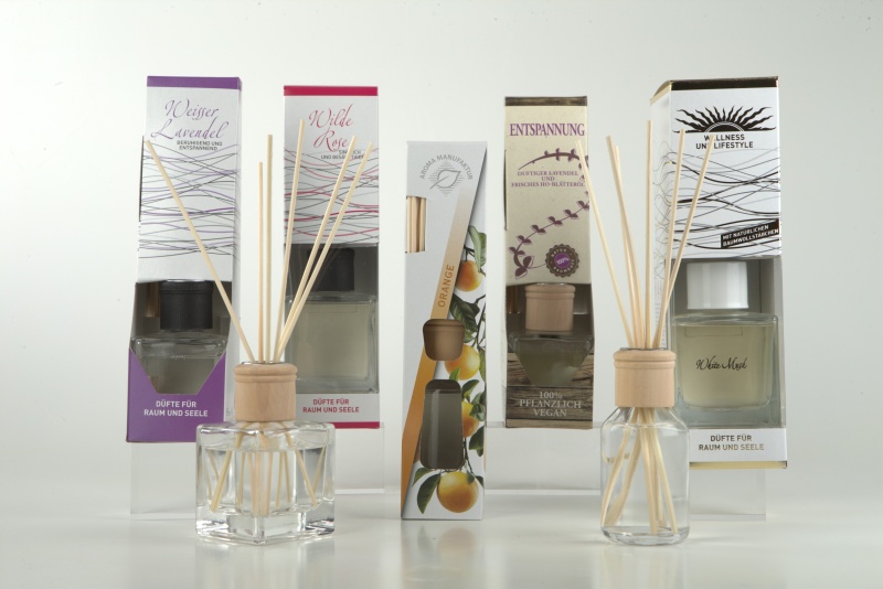 Nebeneinander aufgereihte verschiedene Raumd&uuml;fte mit Holzkappen, Duftst&auml;bchen und den dazugeh&ouml;rigen Produktverpackungen, mit den Aufschriften zum Beispiel Entspannung oder Wellness