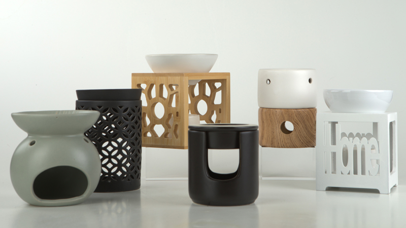 Sammlung verschiedener Duftlampen f&uuml;r &auml;therische &Ouml;le, darunter wei&szlig;e und schwarze Keramikmodelle sowie Mit Holzelementen und ausgestanzten Mustern.